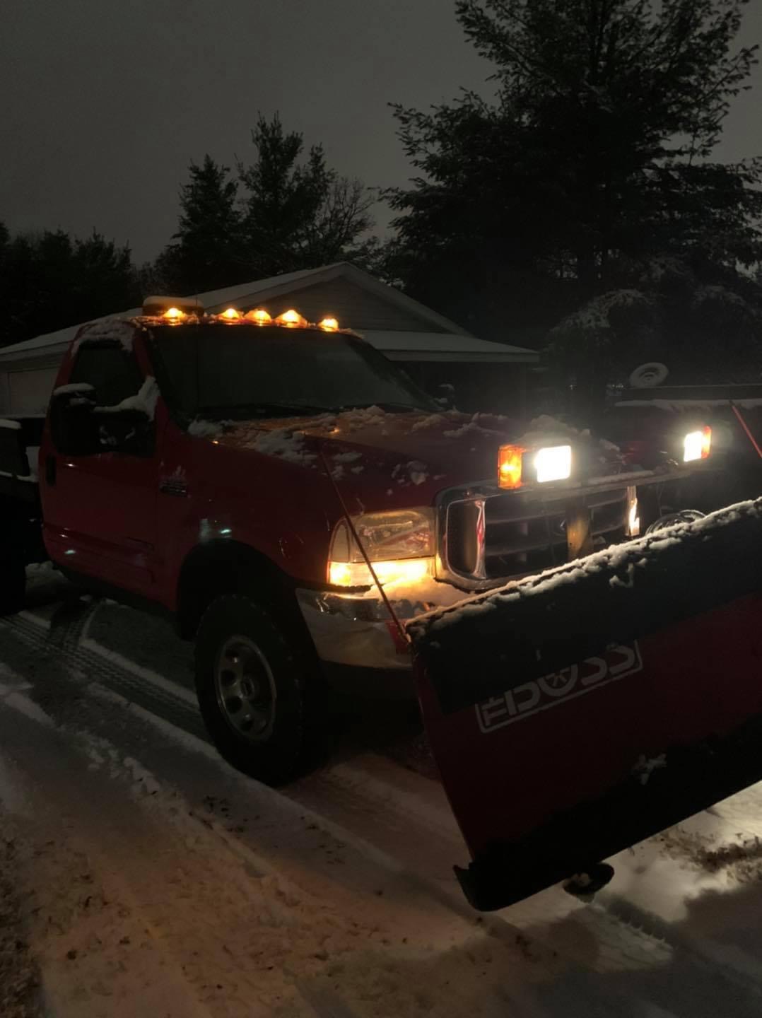 Snowplow truck clearing a driveway at night